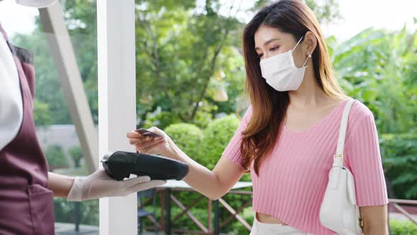 Young Asia female wear face mask making contactless credit card payment and take out food alt
