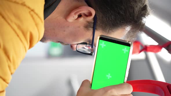 Blank Digital Phone with Chroma Key Green Screen in Hand of Guy Standing Indoors in Public Transport alt