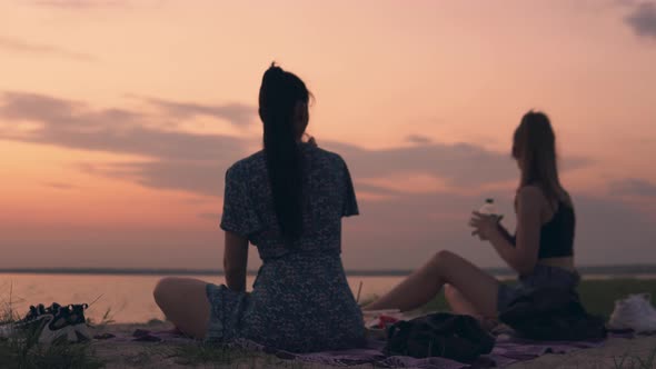 Friends Relaxing on Beach Summer Picnic Sitting on Grass Looking on Sunset