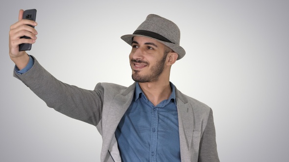 Arabian man in the casual clothes walking and making selfie alt