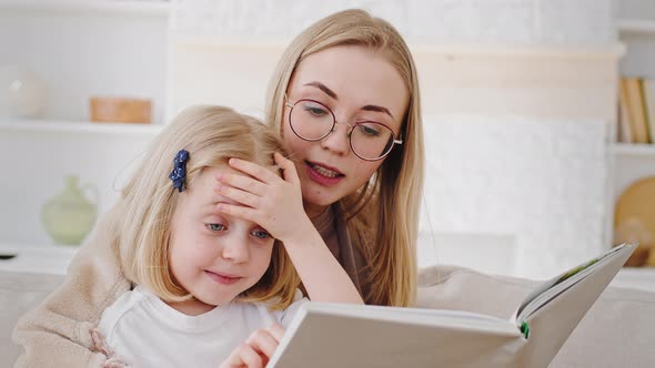 Portrait Caucasian Mother in Glasses Reads Book Fairy Tale to Child Little Daughter Teaches Baby at alt