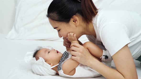 happy mother playing with baby on a bed at home