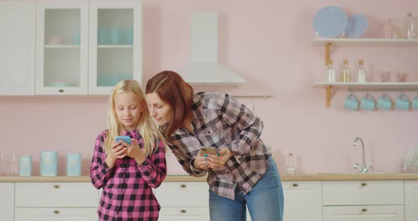 Young 30s Mother and Pre Teen Daughter Surfing Social Media, Texting Messages Using Mobile Phones