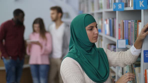Muslim Student Searching for a Book in Library alt