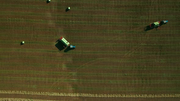 Modern Agricultural Machinery Works in the Field, Harvesting. Tractor Collects Haystacks in Carts