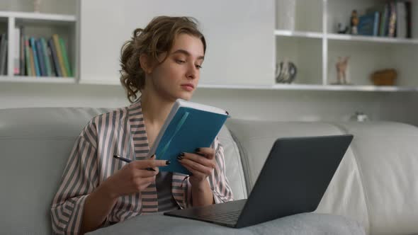 Closeup Young Businesswoman Making Notes Watching Online Conference at Home alt