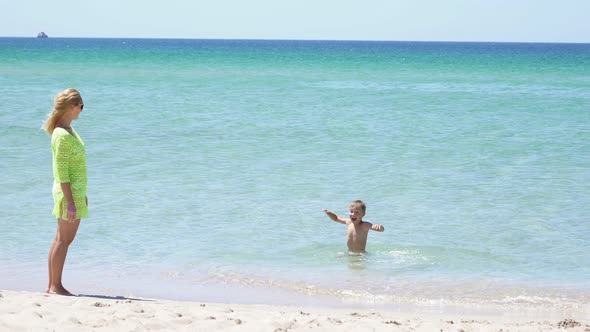 Small Child is Swimming on the Shore of the Azure Sea on a Sunny Day