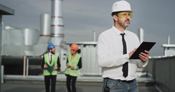 The Young Construction Man Presses on His Gadget alt