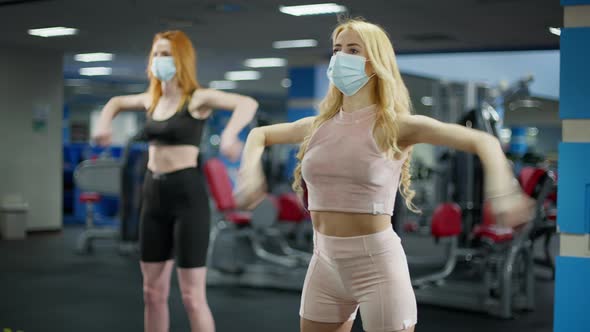Fit Slim Caucasian Women Training Hand Muscles Exercising in Gym Wearing Coronavirus Face Masks alt