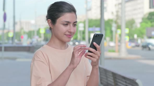 Indian Woman Celebrating Online Success on Smartphone alt