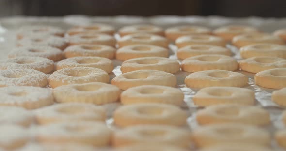 Baker preparing butter cookies with strawberry jam and powdered sugar alt