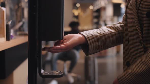 Close Up Washing Hands with an Automatic Alcohol Sanitizer Dispenser at Hotel alt