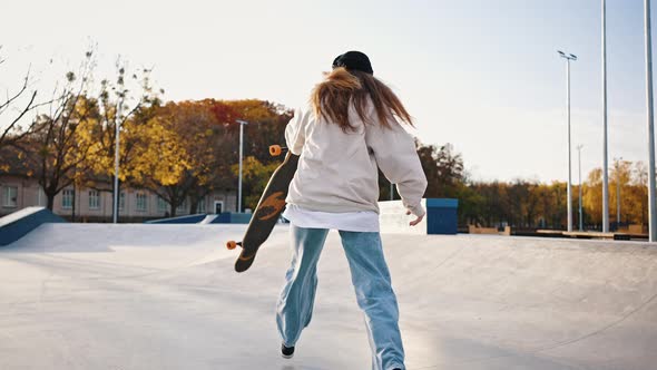 Beautiful Young Girl Riding Longboard in Sunny Weather Skatepark alt