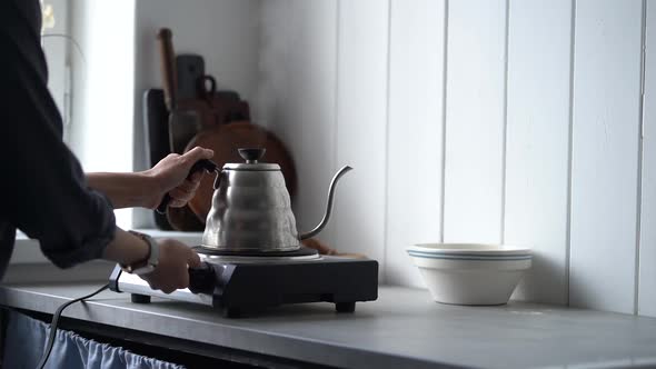 Woman putting coffee kettle on stove alt