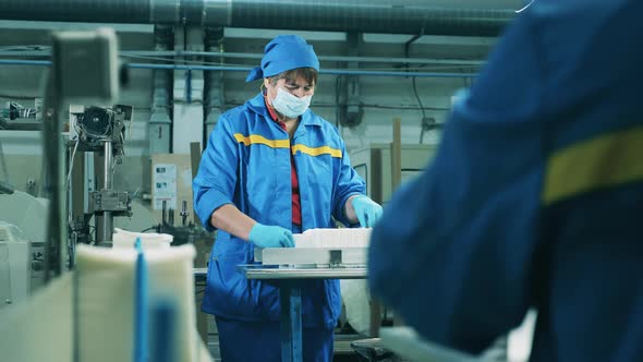Female Factory Workers Placing Paper Tissues Onto a Conveyor alt