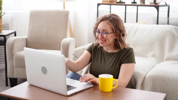 Woman in Glasses Use Laptop Computer While Sitting Sofa with Big Window on Background at Home