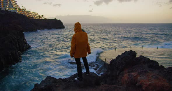A Young Girl Watching the Ocean at the Edge on Top of a Rocky Seashore in  alt