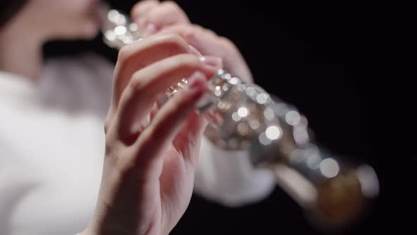 Elegant Girl of European Appearance on a Black Background Plays a Flute alt