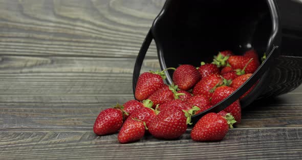 Strawberries in a Small Black Bucket on the Wooden Table alt