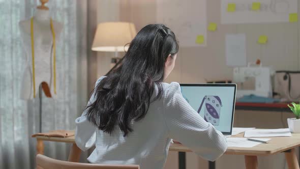 Back View Of A Woman Bag Designer With Layout Bond And Fabric Use Laptop For Designing Bags alt