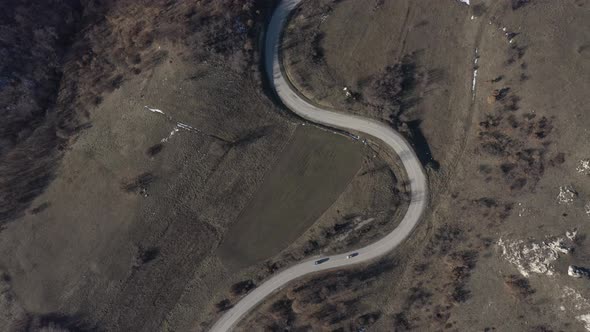 Cars going up the curvy road over the hill 4K drone video alt