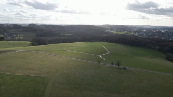 Lush green fields in North Rhine Westfalia on a cloudy winter day. Aerial panning orbit shot alt