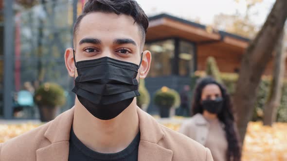 Attractive Brunet Oriental Man in Black Medical Mask Attentively Looking at Camera Standing in alt