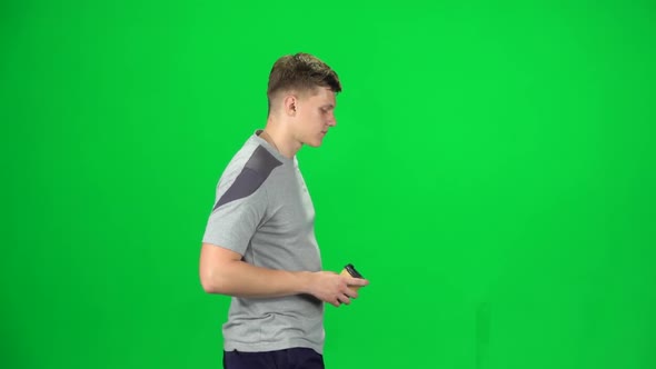 Young Man Walking and Watching on the Phone Something, Drinking Coffee. Chroma Key. Side View. Slow alt