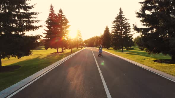 Back View Walking Woman with Baby Stroller on the Empty Road alt