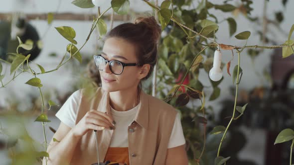 Beautiful Female Worker Misting Plants in Flower Shop alt