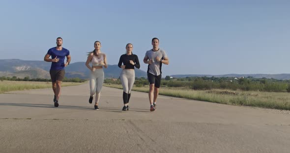 Multiethnic Group of Athletes Running Together on a Panoramic Countryside Road alt