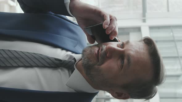 Vertical Shot of Business Man Talking on Phone in Lift alt