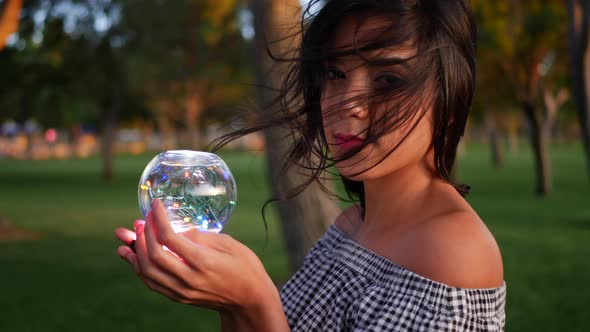 A beautiful gypsy holding a magic glowing crystal ball with an enchanting and mysterious look. alt