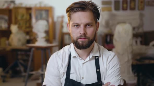 Bearded Stonemason Dressed in Workwear Sitting at His Workplace in Studio alt