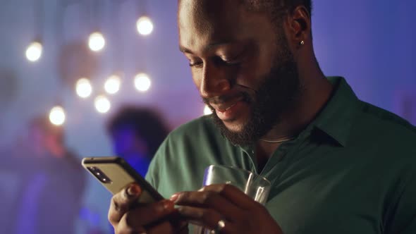 Black Man Using Smartphone During Home Party alt