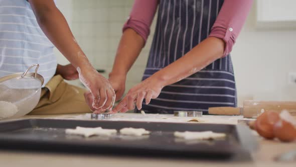 African american mother and son in kitchen cooking, looking at tablet alt