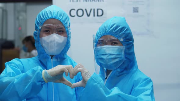 Two Doctors in Protective Suits During the Period of the Epidemic Show a Sign of Life and Heart in alt