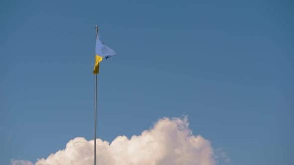 The national flag of Ukraine is developing in the wind against the background of clouds