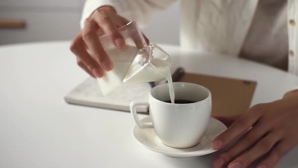 Joyful Relaxed Woman Adds Vegetable Milk To Coffee, Hand Of A White Girl Pours Milk From A Milk alt