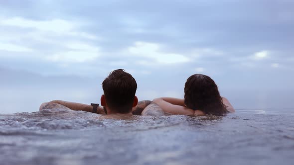 Couple Relaxing in an Infinity Pool With the View of the Majestic Blue Sky alt