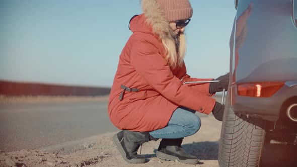 Woman Check Car Tire Pressure. Vehicle Trouble On Road On Vacation Trip. Female Trying Fix Car Tire. alt