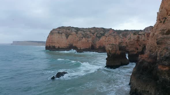 Aerial Drone Flying Above Atlantic Ocean Reveals Scenic Colored Rocky Cliff Coastline in Lagos alt