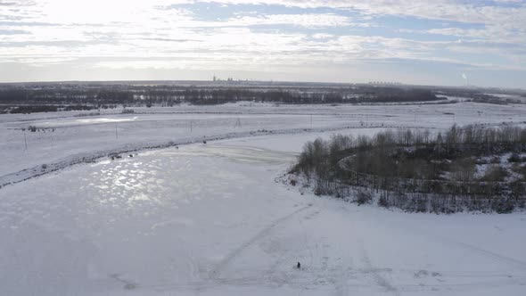 A Fisherman Fishing in Winter Time on Ice Covered River