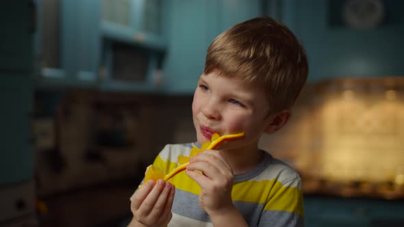 Kid eating orange fruit holding in hands alt