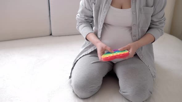 Authentic Cute Pregnant Woman with Pop It Feeling Happy at Home with Belly