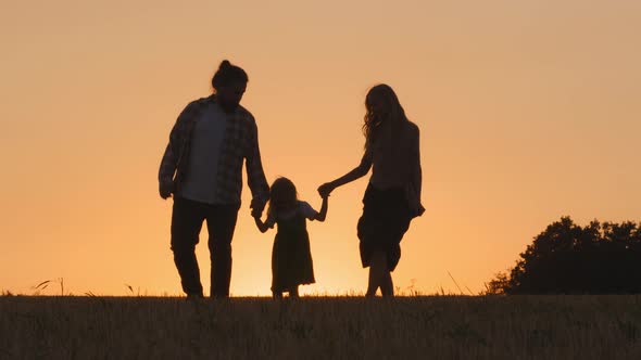 Silhouette of Group of Three People Happy Carefree Family Active Parents with Little Daughter Small alt