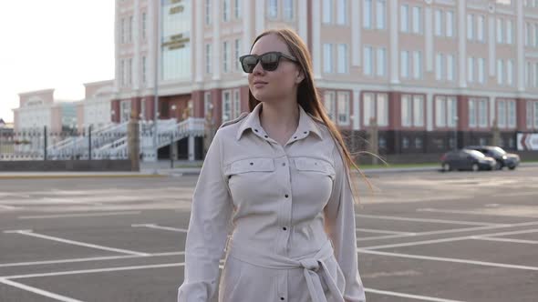 Beautiful Young Girl with Glasses Walks Through the City and Looks Around