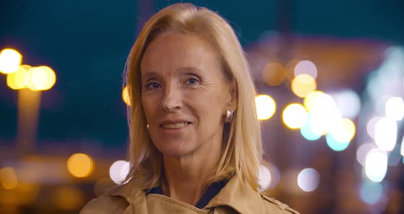 Bokeh Shot of Elegant Mature Woman Looking at Camera Outdoors alt