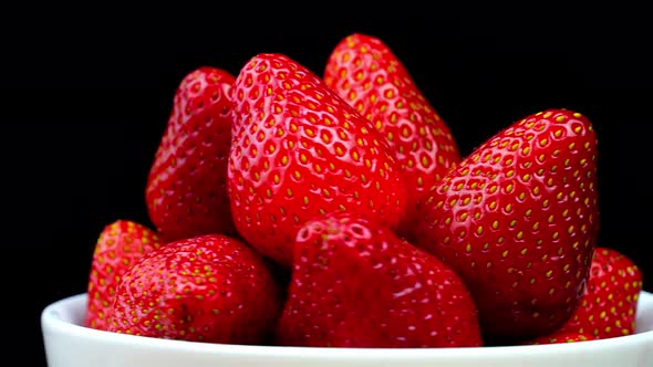 Strawberries without tails lie in white bowl or plate. It rotates alt