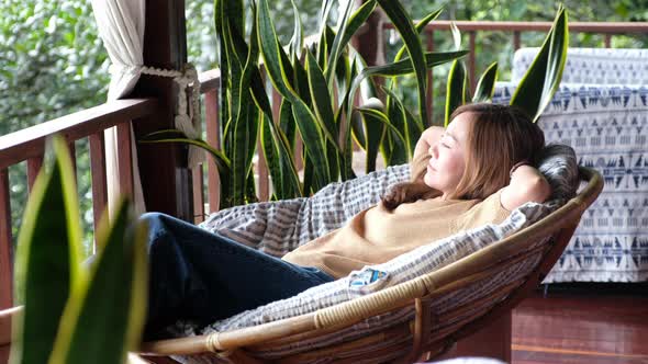 A young woman lying and relaxing on sofa at home with a beautiful nature view